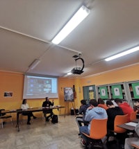 a group of people sitting at tables in a classroom