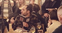 a group of people sitting at a table and reading a book